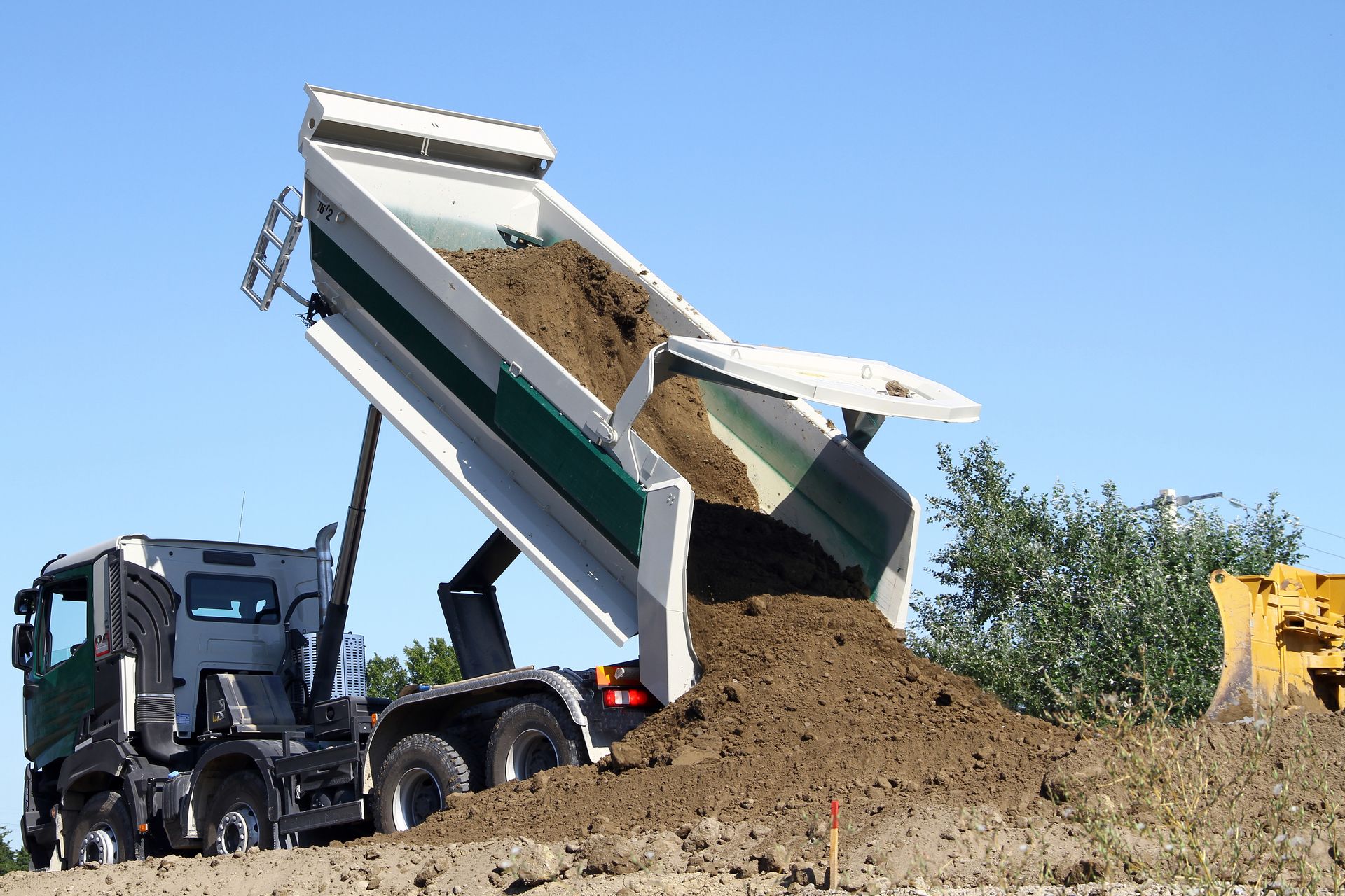 Camion-benne déchargeant de la terre sur un chantier de construction.