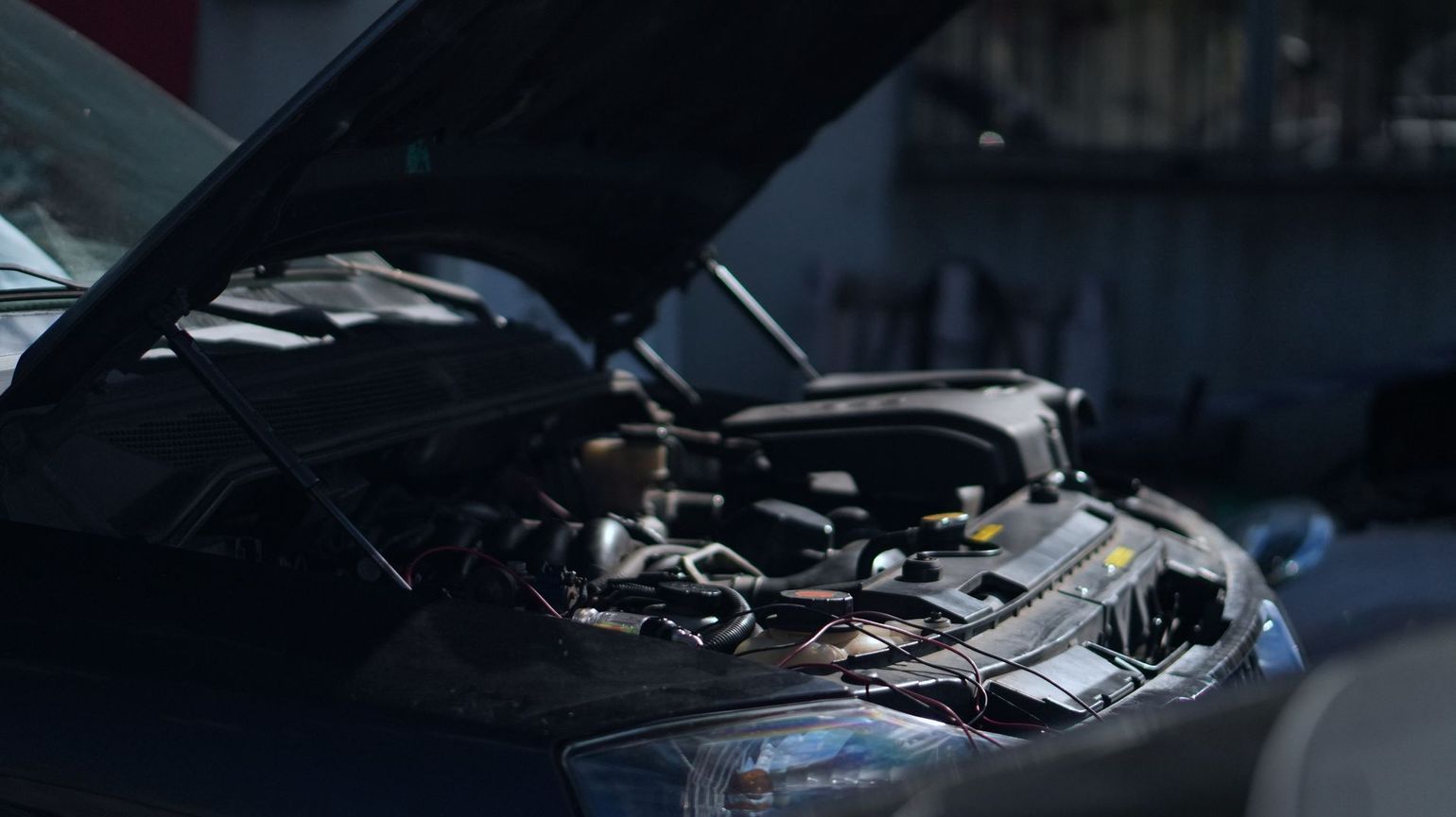 Mécanicien aux mains gantées utilisant une clé sur un moteur de voiture dans un atelier de réparation.