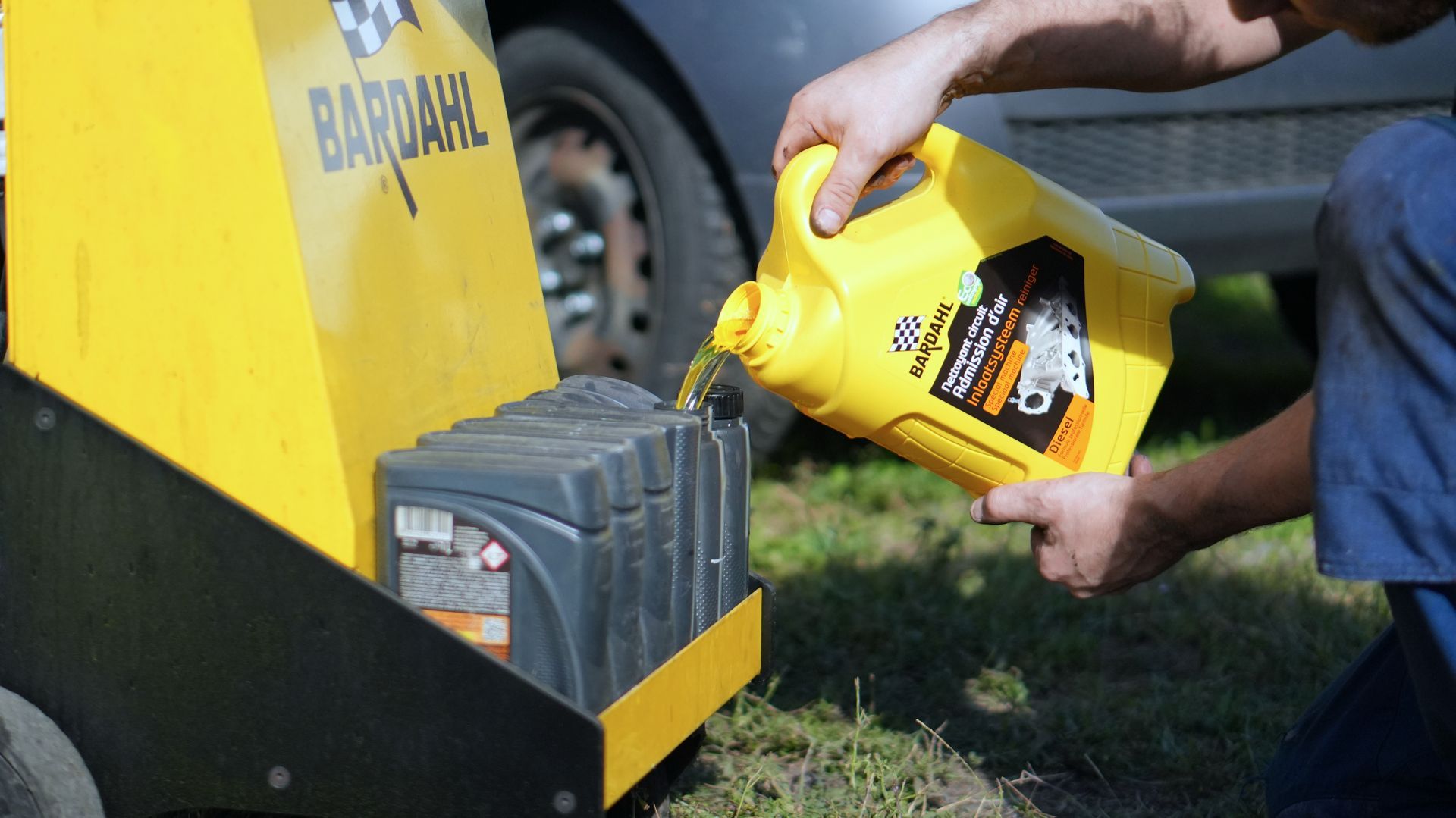 Un mécanicien verse de l'huile d'une bouteille dans le moteur d'une voiture. Gros plan dans un garage.