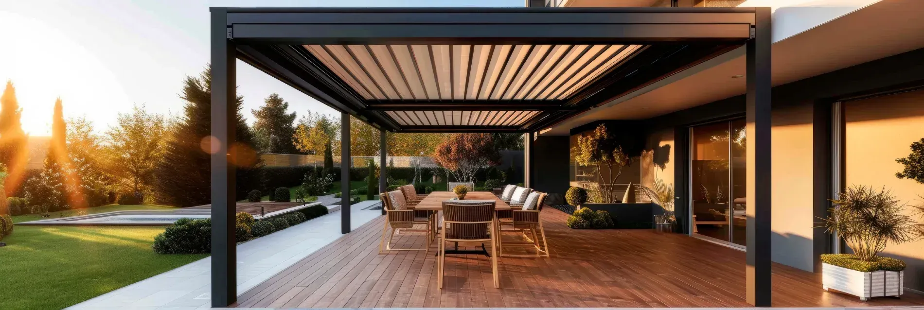 Pérgola sobre terraza de madera con mesa de comedor y sillas, cerca de una casa y jardín con luz solar.