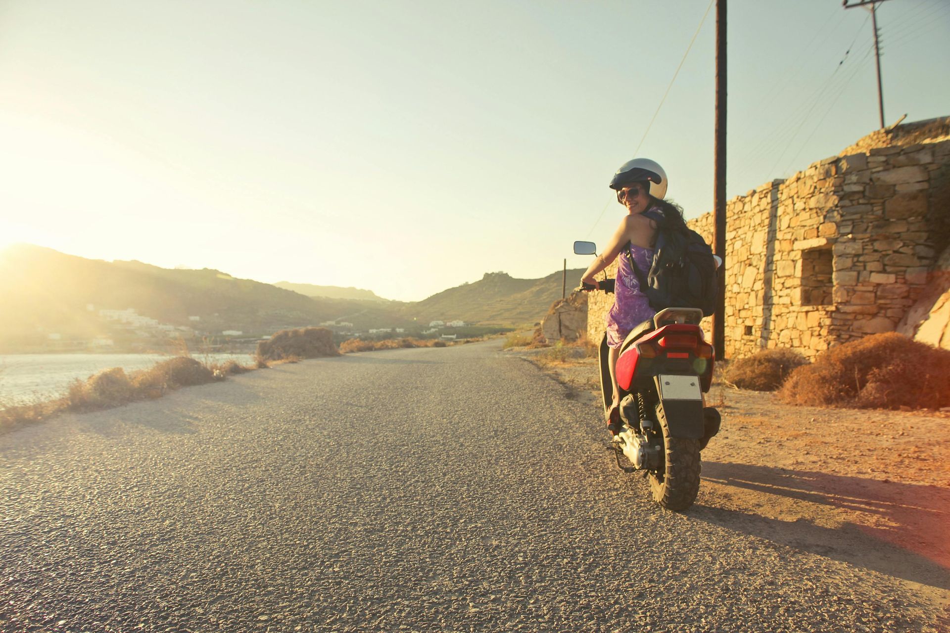 Una mujer va conduciendo una motocicleta por una carretera.