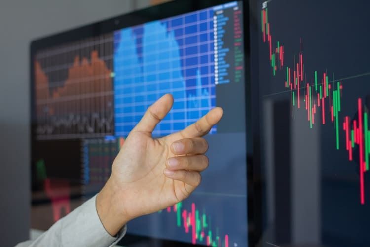 Una persona está señalando un gráfico de acciones en la pantalla de una computadora.