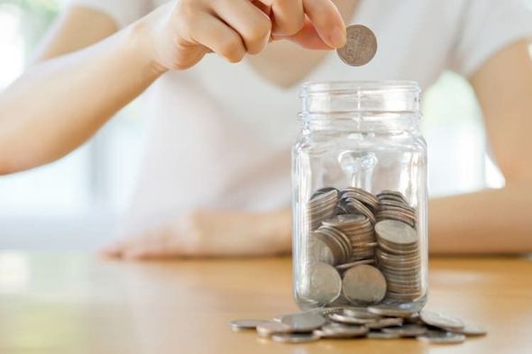 Una persona está poniendo una moneda en un frasco lleno de monedas.