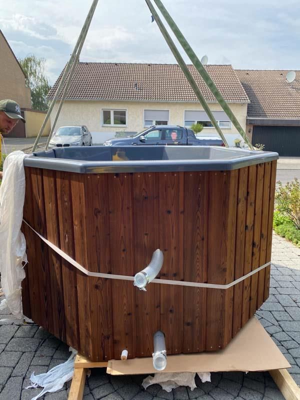 Ein hölzerner Whirlpool wird von einem Kran angehoben