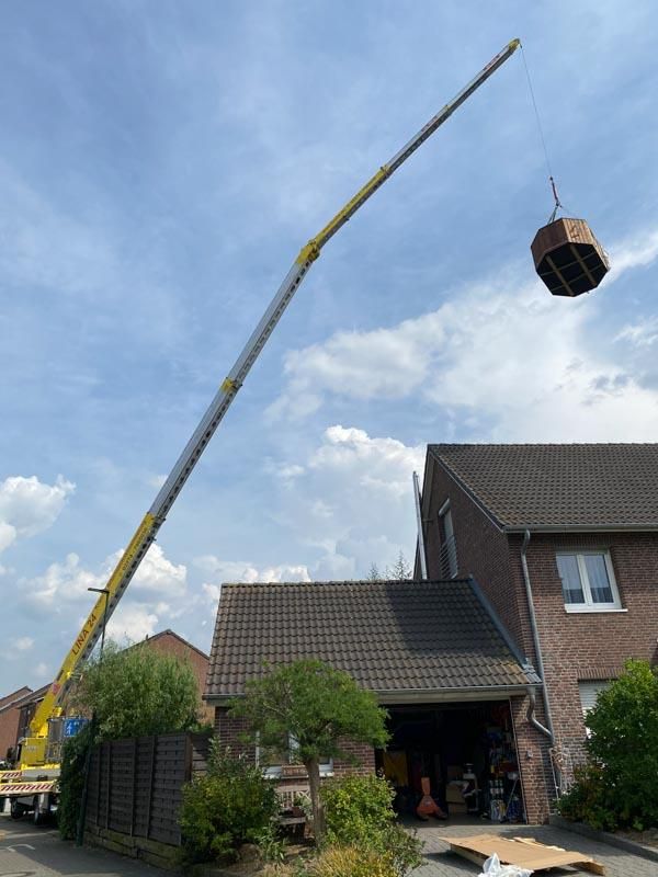 Ein Kran hebt eine Kiste vor einem Haus in die Luft