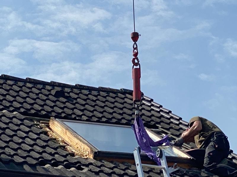Ein Mann auf einer Leiter arbeitet auf einem Dach