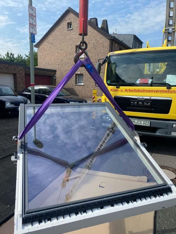 Ein Kran hebt ein Fenster vor einem Yellow Man-LKW