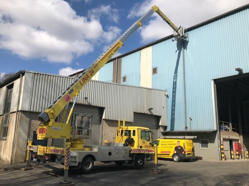 Ein gelber Kranwagen steht vor einem Gebäude