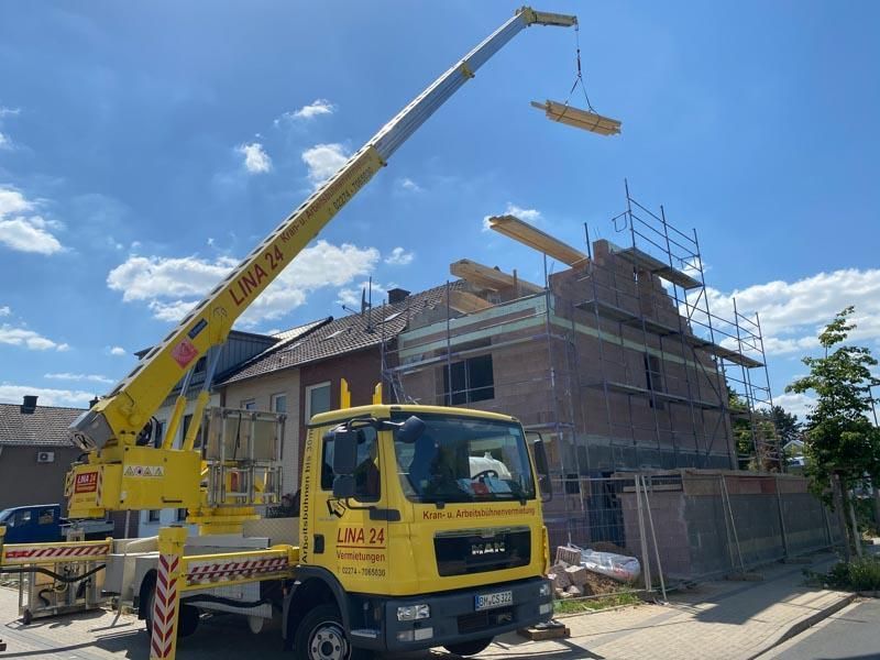 Ein gelber LKW mit einem Kran an der Rückseite