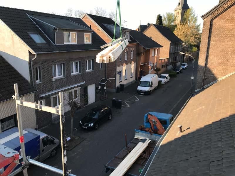 Ein großes Stück Holz wird von einem Kran in ein Wohngebiet gehoben