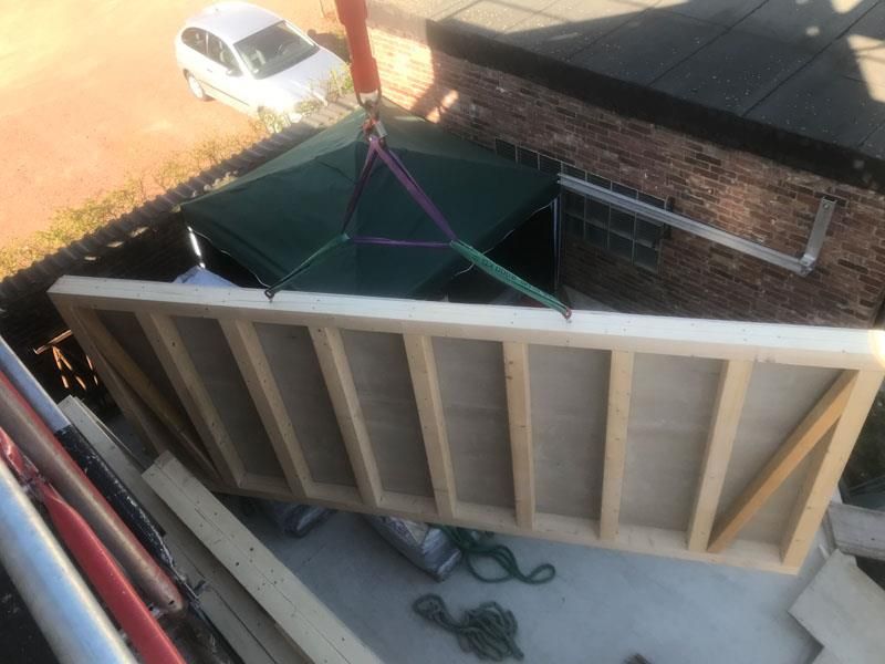 Ein großes Stück Holz wird von einem Kran angehoben.