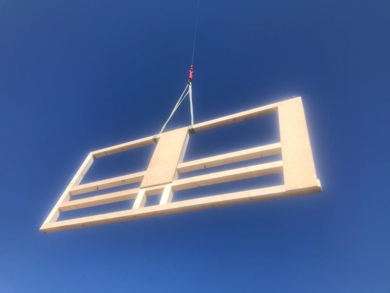 Ein Stück Holz wird von einem Kran in die Luft gehoben