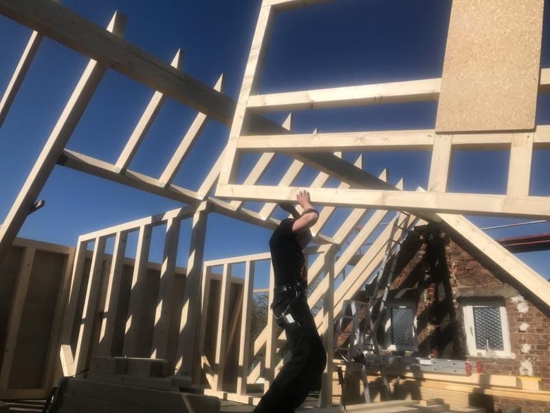 Ein Mann steht vor einer Holzkonstruktion