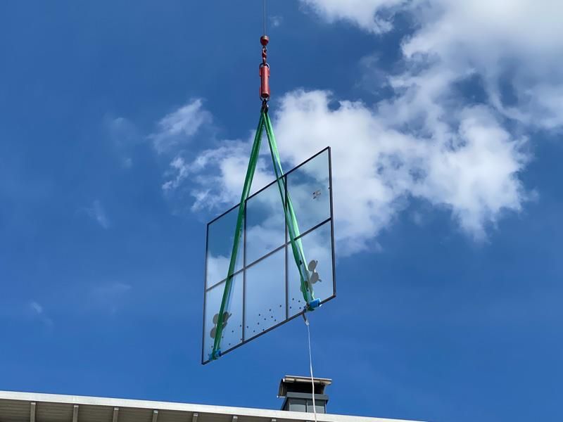 Ein großes Stück Glas wird von einem Kran angehoben