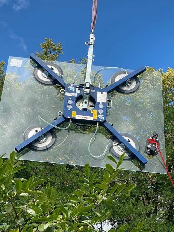 Ein großes Stück Glas wird von einem Kran angehoben.