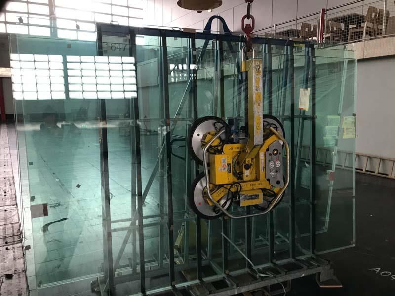 Ein großes Stück Glas wird von einer Maschine angehoben.