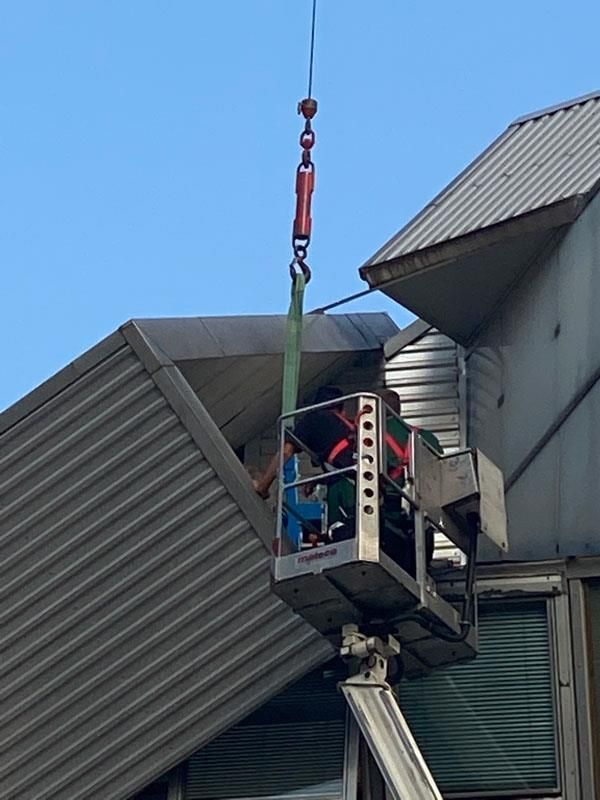 Ein Mann in einem Eimer wird von einem Kran in die Luft gehoben