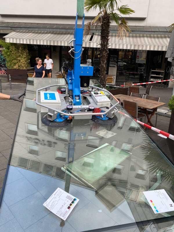 Ein großer Glastisch wird von einer Maschine angehoben.