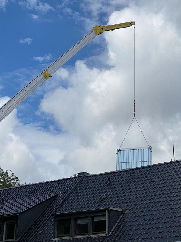 Ein Kran hebt einen Container auf ein Dach