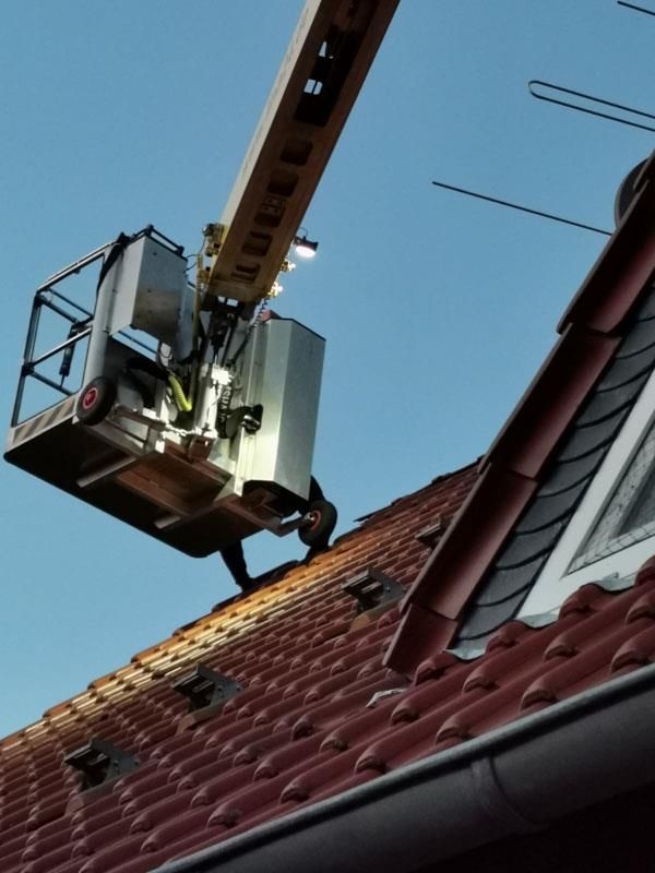 Ein Mann arbeitet mit einem Kran auf dem Dach eines Gebäudes