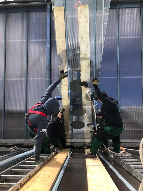 Eine Gruppe Männer arbeitet an einem großen Stück Glas.