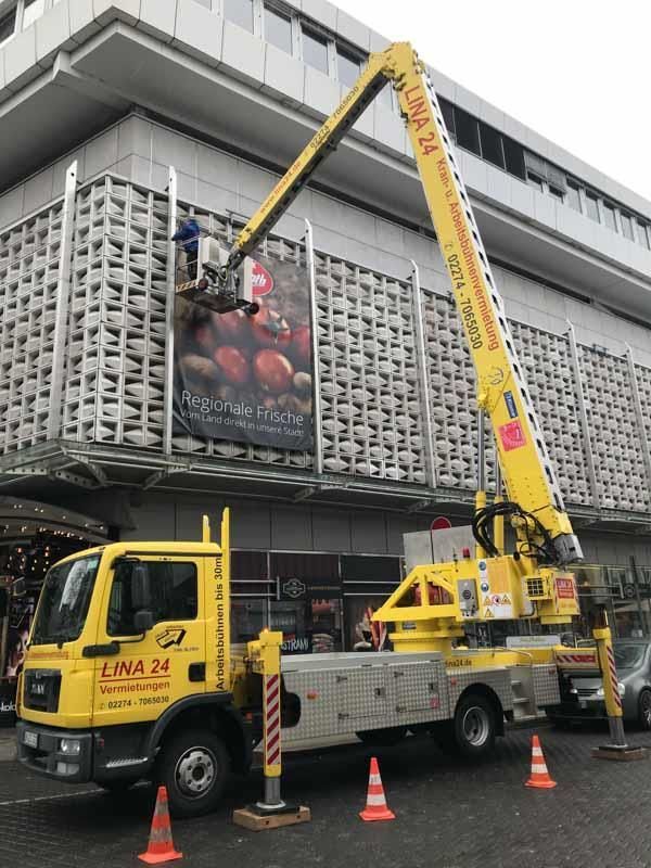 Ein gelber Kranwagen steht vor einem Gebäude