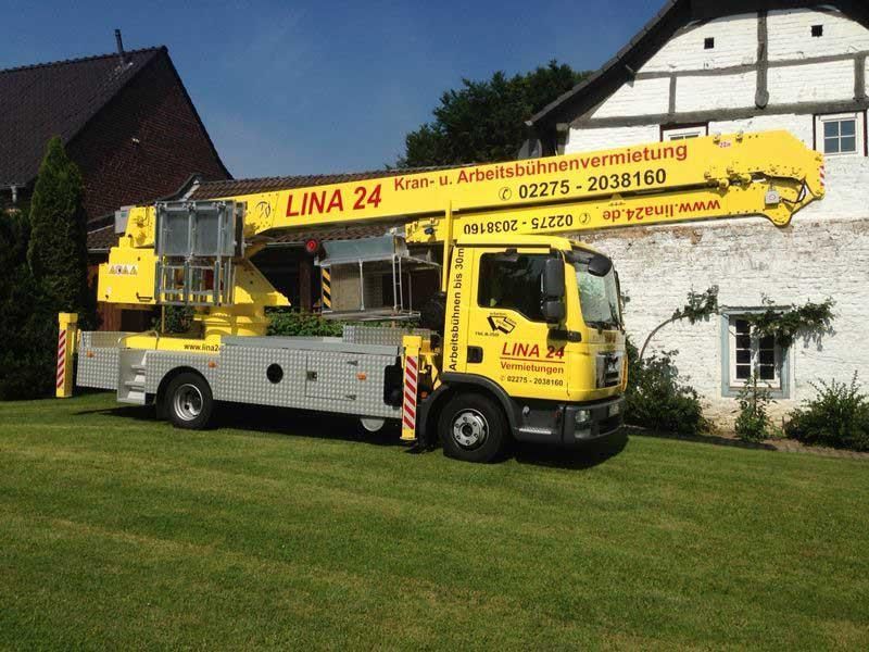 Ein gelber Lina 24-LKW steht vor einem Haus
