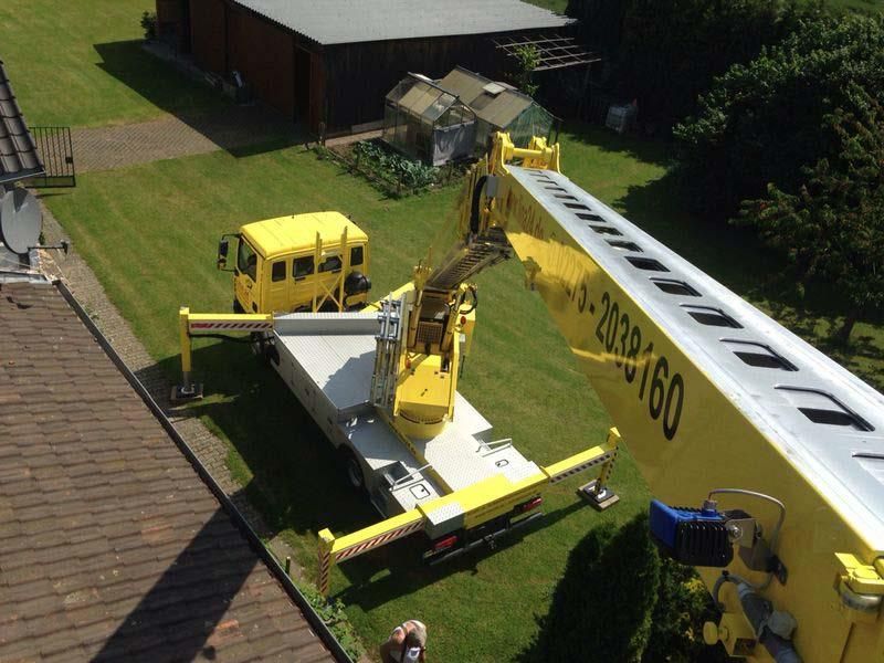 Ein gelber LKW mit einem Kran an der Rückseite