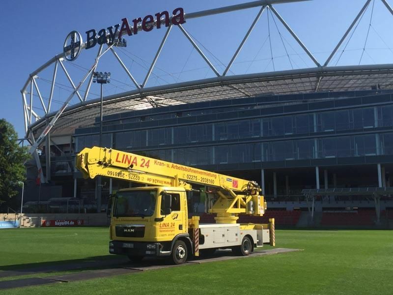 Ein gelber LKW steht vor einem Gebäude mit der Aufschrift „Bayern“