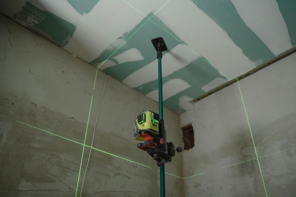 Una persona está usando un nivel láser para medir el techo de una habitación.