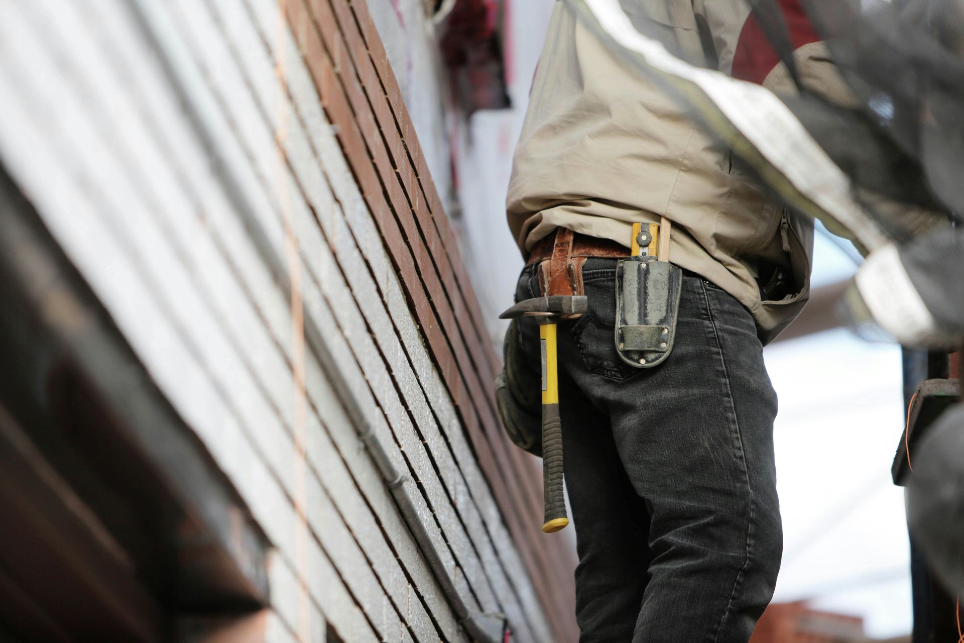 Un trabajador de la construcción está midiendo una pared de ladrillos con una cinta métrica.