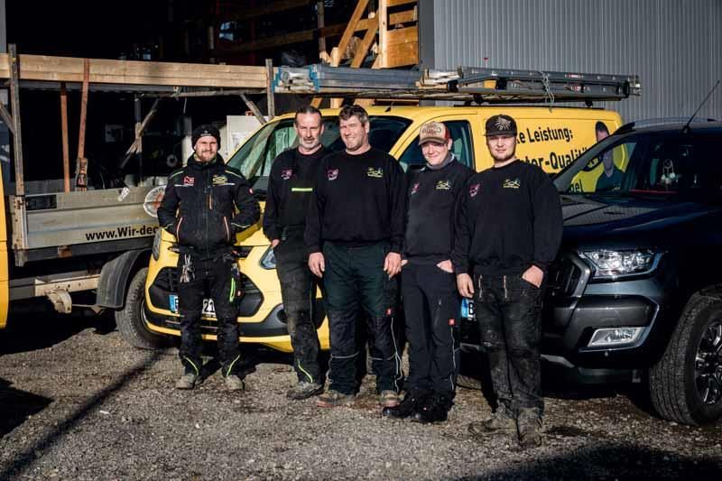 Eine Gruppe Männer posiert vor ihren Lieferwagen für ein Foto.