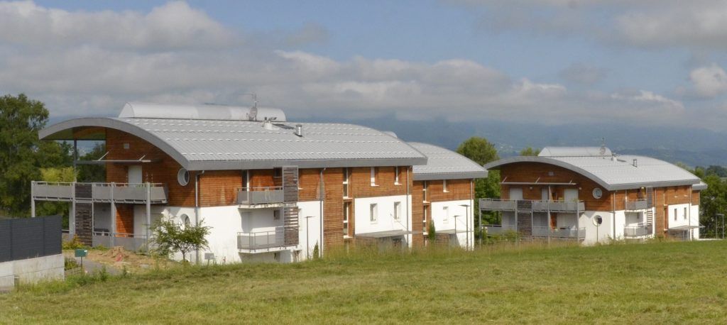 Un jardin avec trois immeubles en ossature de bois