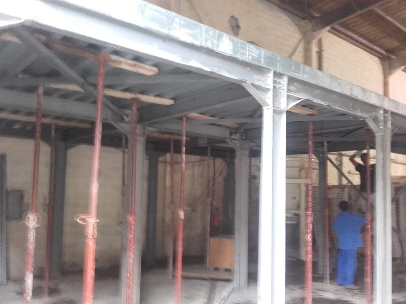 Chantier : échafaudage métallique soutenant une structure. Ouvriers visibles.