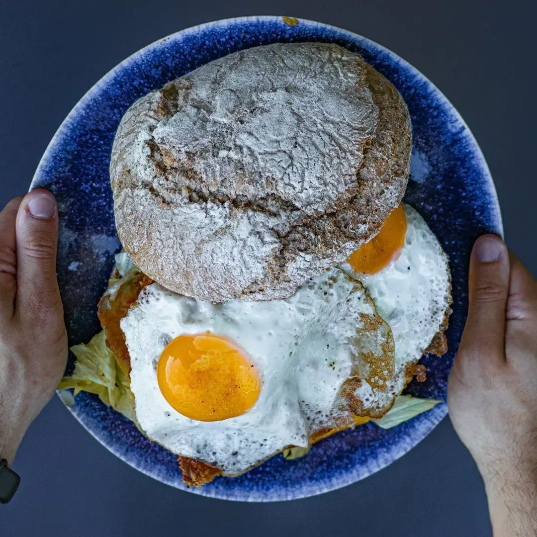 Una persona sostiene un plato de comida con huevos encima.