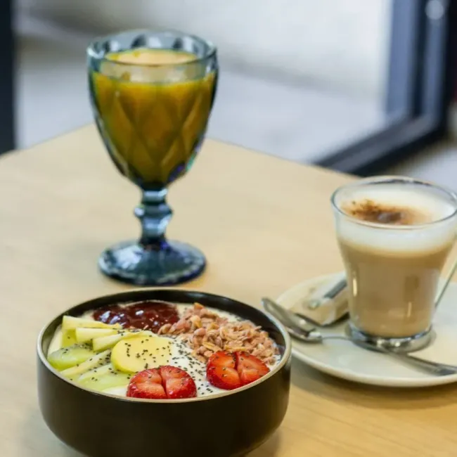 Un bol de fruta y una taza de café sobre una mesa.