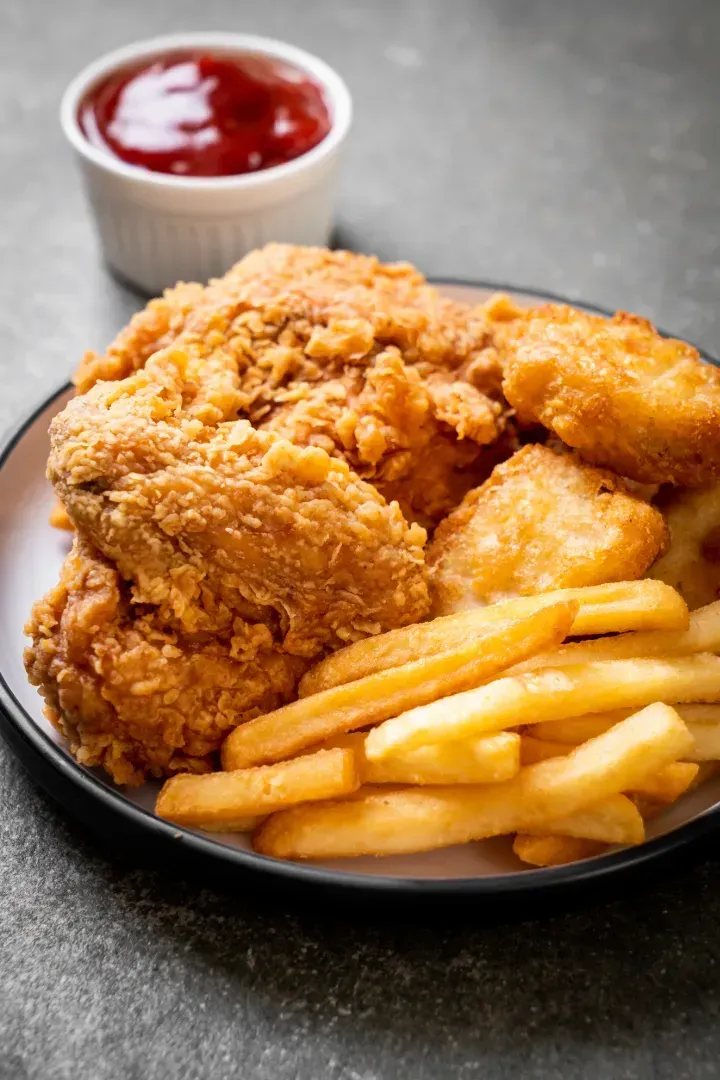 Un plato de pollo frito y papas fritas con ketchup.