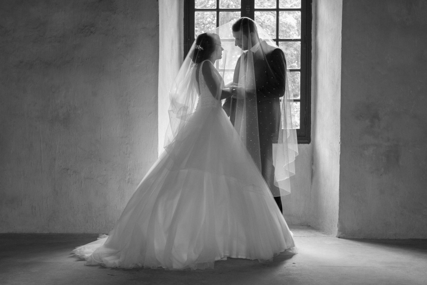 Mariés en noir et blanc devant une fenêtre