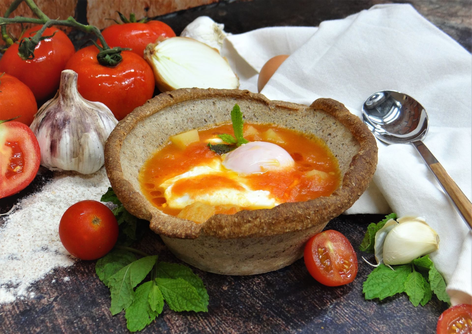 Uma sobremesa portuguesa, coberta com creme amarelo e amêndoas, servida numa caixa castanha sobre uma mesa de madeira.