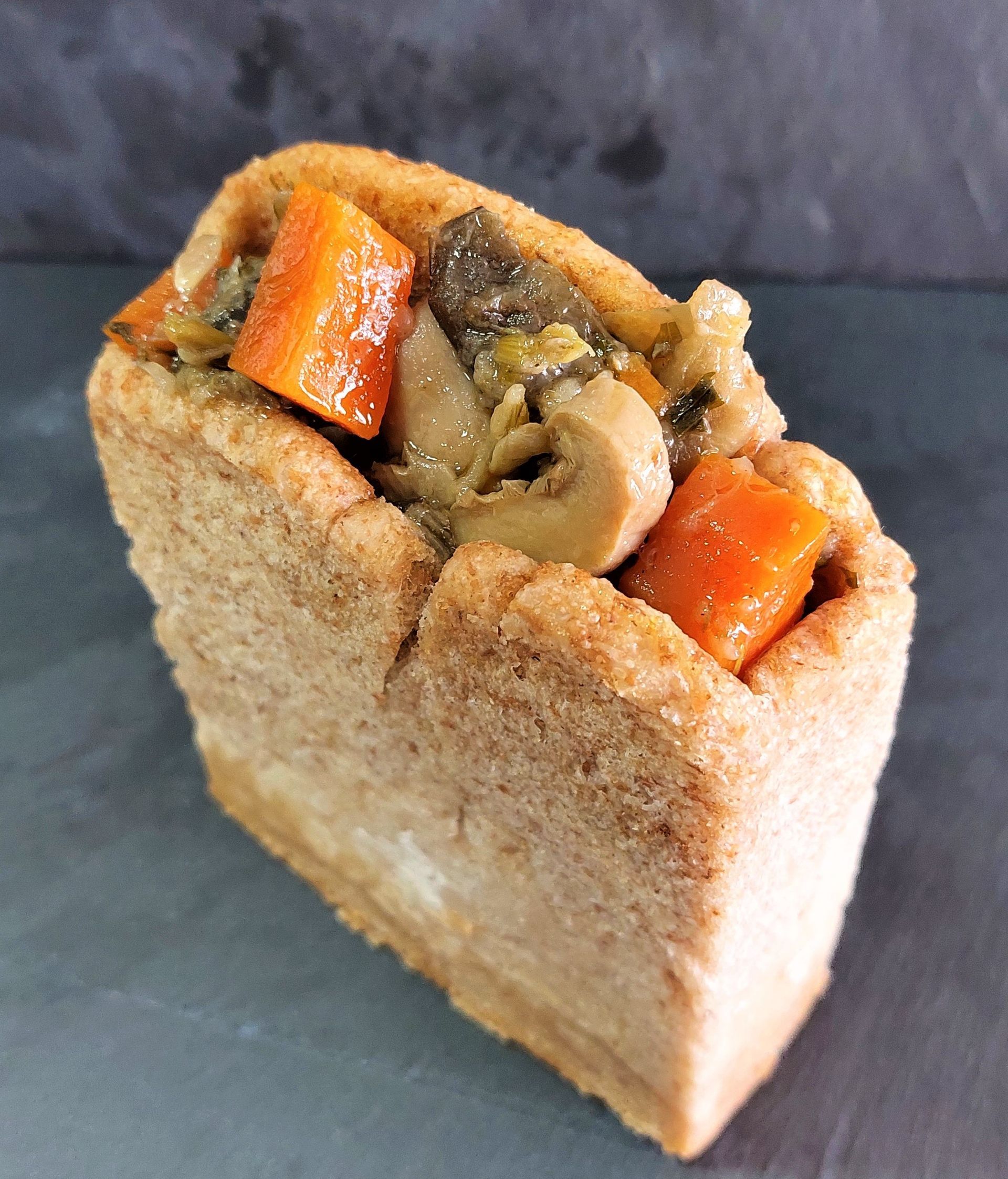 Legumes e um pão sobre uma tábua de madeira.