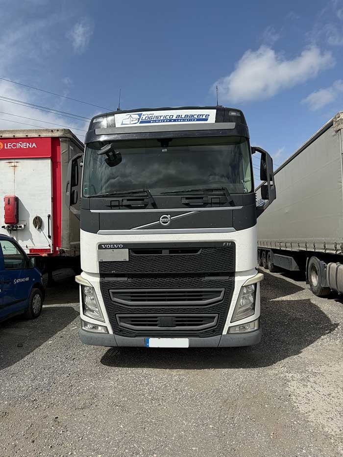 Un camión Volvo está estacionado en un estacionamiento al lado de otros camiones.