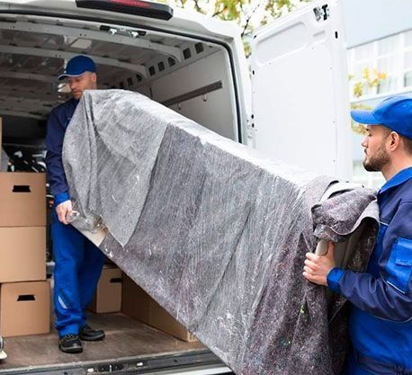 Un hombre saca un mueble grande de una camioneta.