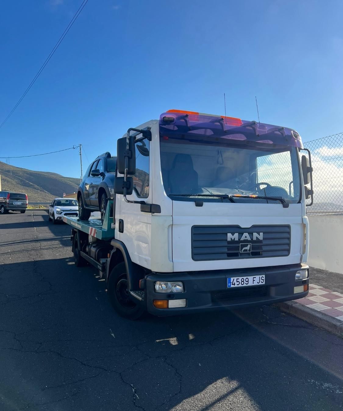 Un hombre con una grúa está estacionado al costado de la carretera.