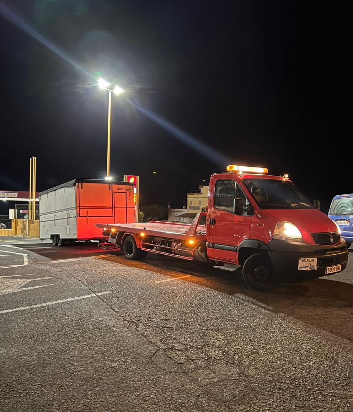 Una grúa roja está remolcando un remolque en un estacionamiento por la noche.