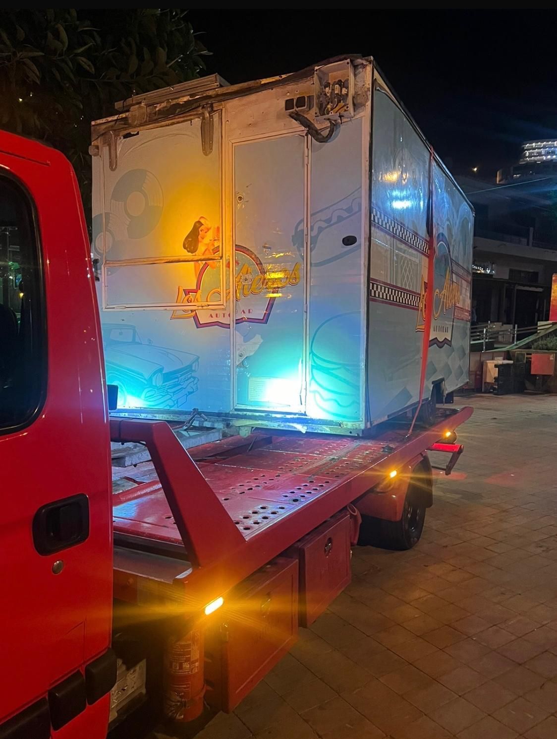 Una grúa roja está remolcando una caja blanca grande.