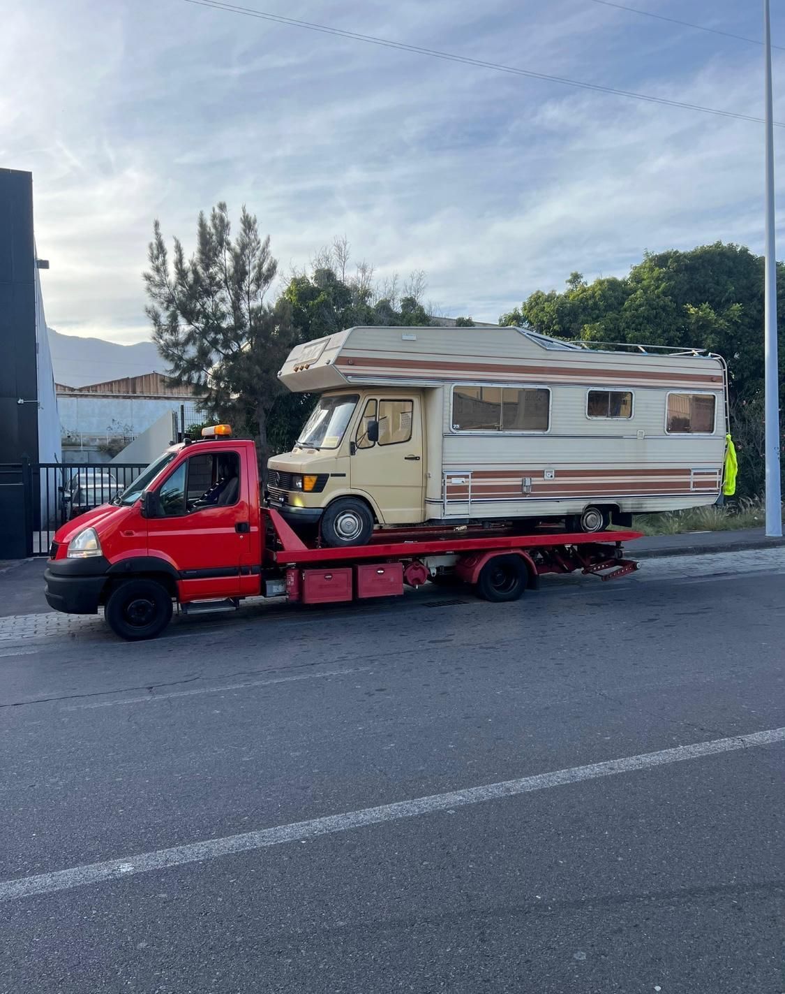 Una grúa roja está remolcando una caravana por la carretera.