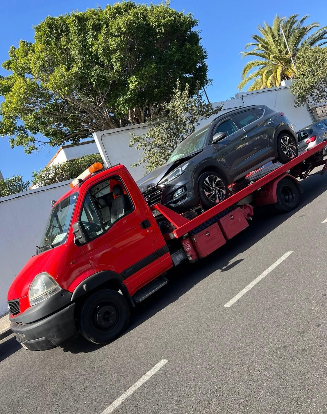 Una grúa roja transporta un coche averiado