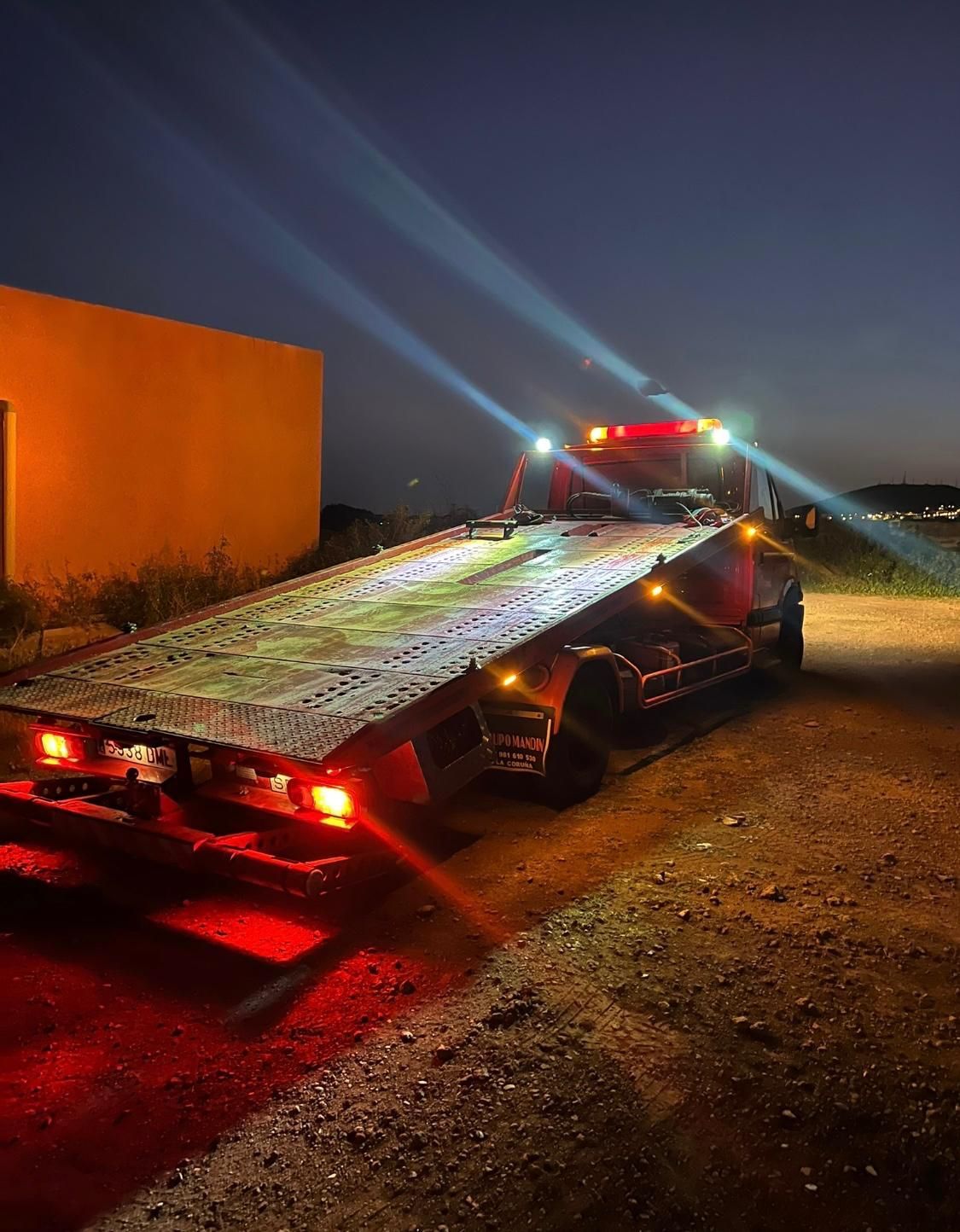 Una grúa está estacionada al costado de la carretera por la noche.