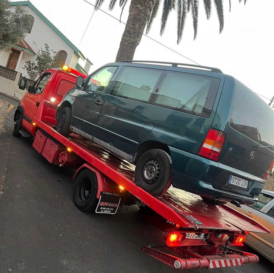 Una camioneta azul está siendo remolcada por una grúa roja.