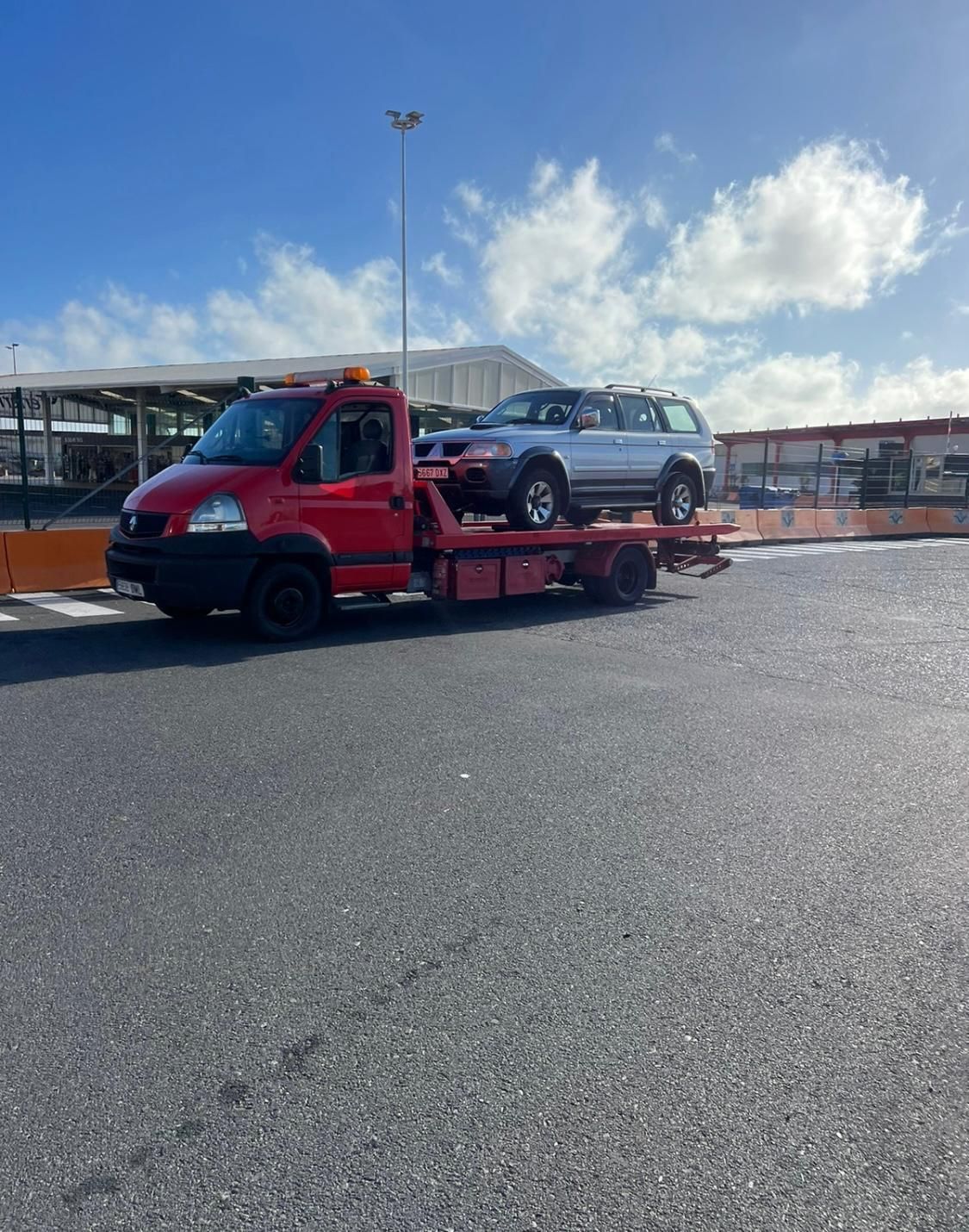 Una grúa roja lleva una camioneta todoterreno plateada en la parte trasera.